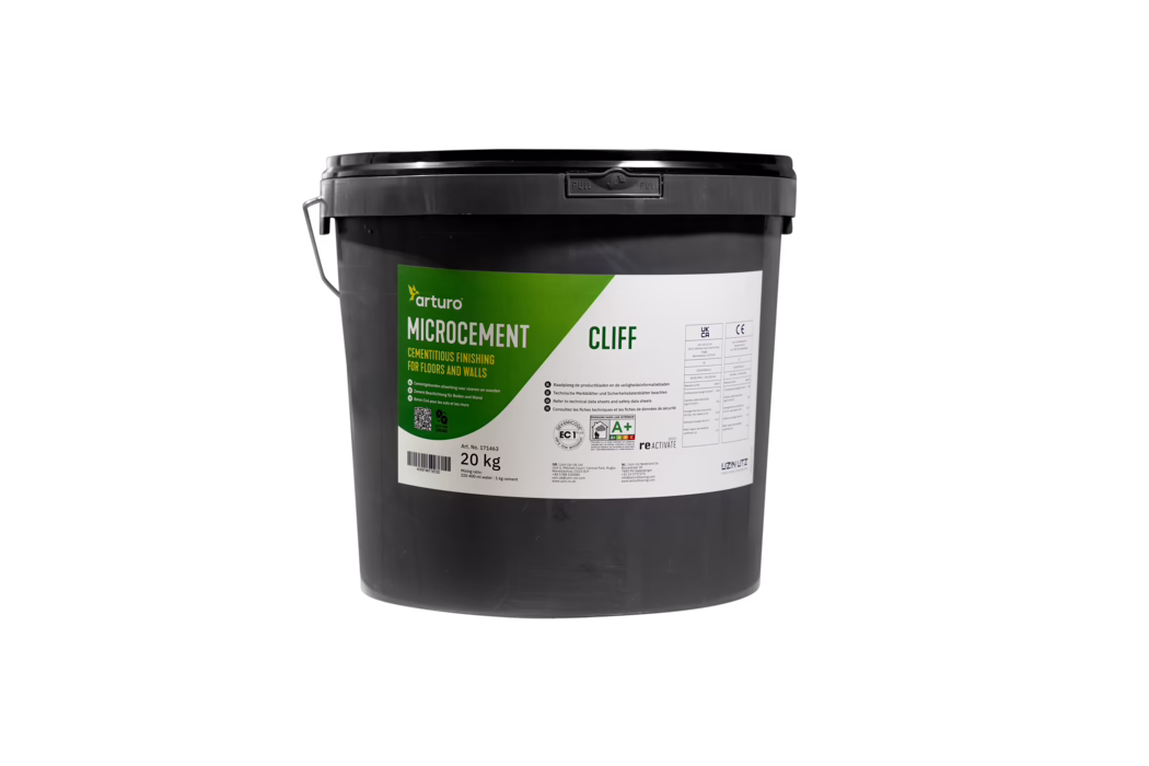 Arturo_Dummy_Microcement_20kg_2022-08 Vooraanzicht van een zwarte kunststofemmer van 20 kg van Arturo Microcement 'Cliff' met groen-wit etiket, metalen handvat en verzegelde zwarte deksel, een cementachtige afwerkingsproduct voor vloeren en wanden; vrijstaand op een witte achtergrond.